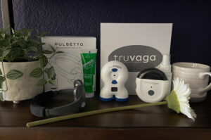 Handheld vagus nerve stimulation devices displayed on a shelf with related supplies, a plant, a mug, and a flower in a wellness space.
